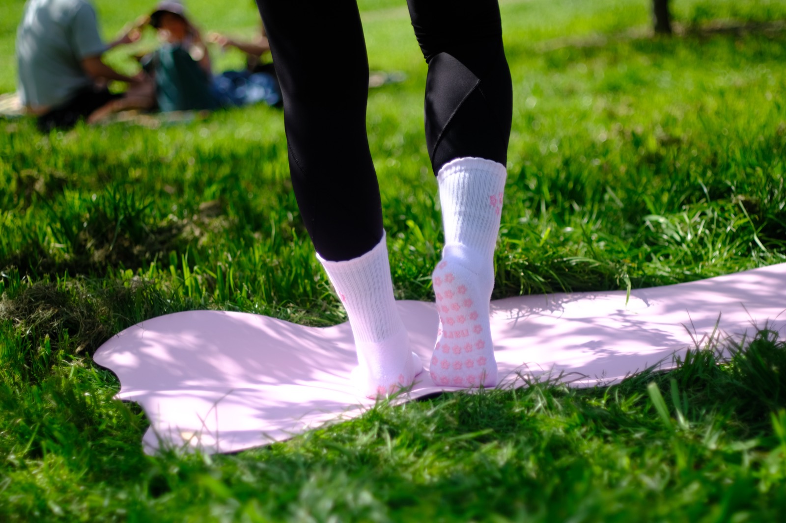 Blooming Sakura grip socks with flower-shaped grip, standing on a pink mat